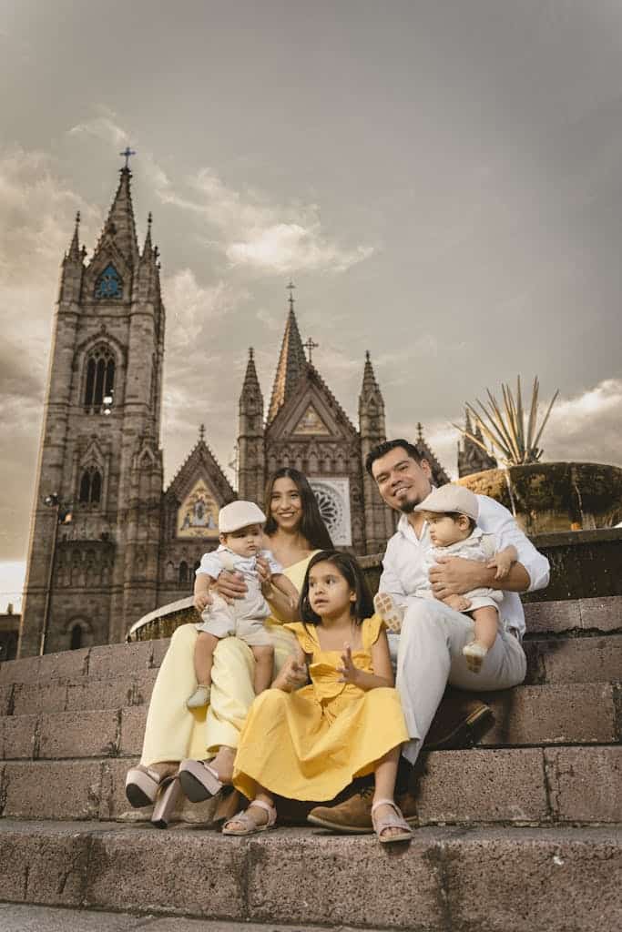 Family of five smiling and posing on steps in front of a historic gothic-style church.