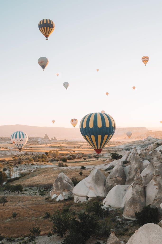 Stunning view of hot air balloons in the sky over Cappadocia's unique rock formations at sunrise.