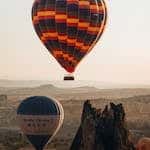 Breathtaking view of vibrant hot air balloons soaring above Cappadocia at sunrise.
